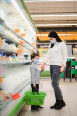 Obraz premium Authentic shot of mother and son wearing medical masks to protect themselves from disease while shopping for groceries together in supermarket.