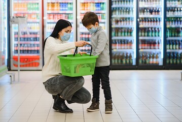 Portrait of a mother and her little son wearing protective face mask at a supermarket during the coronavirus epidemic or flu outbreak. Empty space for text.