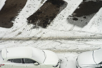 Car parking in winter time. Cars covered with thick layer of snow and empty parking spaces in snow. Aerial view