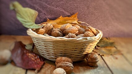 w koszyczku orzechy włoskie na stole dębowym w otoczeniu liści © Józef
