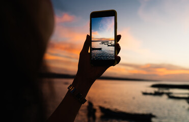 Crop woman taking photo of sunset