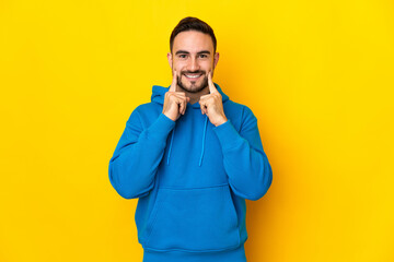 Young caucasian handsome man isolated on yellow background smiling with a happy and pleasant expression