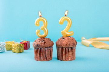 32 Number gold candle on a cupcake against a pastel blue background thirty second year celebration
