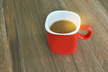 Obraz premium Red coffee cup on wooden table for people drinking in morning or relaxing time.