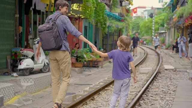 Young father and his son travelers explore the area of the Hanoi city where railway paths go through a residential area. Hanoi Train Street is a famous tourist destination
