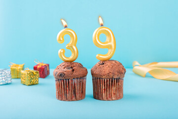 39 Number gold candle on a cupcake against a pastel blue background thirty ninth year celebration