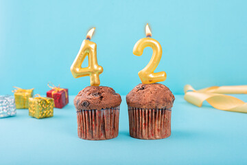 42 Number gold candle on a cupcake against a pastel blue background forty second year celebration