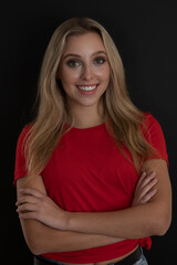 Obraz premium Portrait ofa beautiful young woman in red tshirt over black background