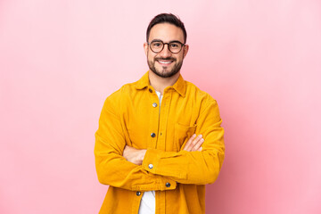 Young caucasian handsome man isolated on pink background keeping the arms crossed in frontal position