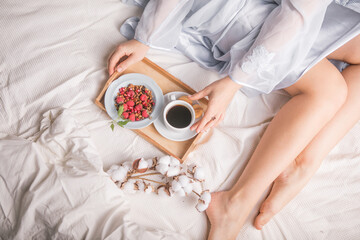 Breakfast in bed with coffee cup and granola on tray. Copy Space. Cozy breakfast. Man bringing woman breakfast in bed with theater tickets to celebrate wedding anniversary