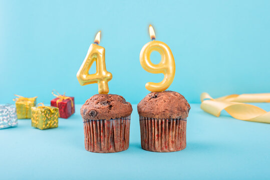 49 Number gold candle on a cupcake against a pastel blue background forty ninth year celebration