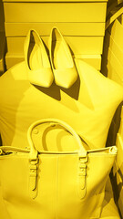 Bright illuminating yellow high heel shoes, handbag and glasses on gray color background.