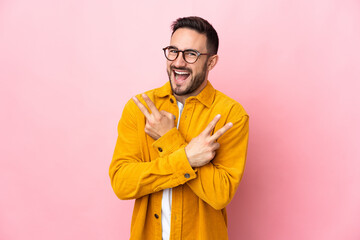 Young caucasian handsome man isolated on pink background smiling and showing victory sign