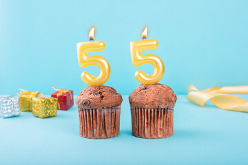 55 Number gold candle on a cupcake against a pastel blue background fifty fifth year celebration