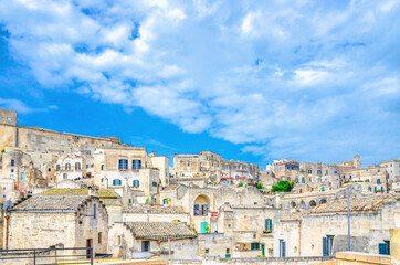 Fototapeta na wymiar Sassi di Matera panoramic view of historical centre Sasso Caveoso of old ancient town with rock cave houses, blue sky and white clouds, UNESCO World Heritage, Basilicata, Southern Italy