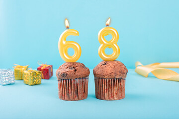 68 Number gold candle on a cupcake against a pastel blue background sixty eight year celebration