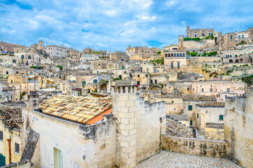 Fototapeta premium Sassi di Matera, historical centre Sasso Caveoso of old ancient town with rock cave houses, blue sky and white clouds, UNESCO World Heritage, Basilicata, Southern Italy
