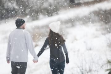 Young couple walking and holding hands in snow