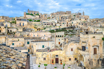 Fototapeta na wymiar Sassi di Matera, historical centre Sasso Caveoso of old ancient town with rock cave houses, blue sky and white clouds, UNESCO World Heritage, Basilicata, Southern Italy