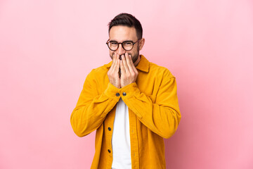 Young caucasian handsome man isolated on pink background happy and smiling covering mouth with hands