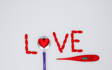 The word love is made of red pills and a stethoscope with a heart, thermometer on a white background with a copy space. Concept of Valentines day, medical flatly.