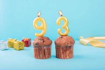 93 Number gold candle on a cupcake against a pastel blue background ninety three year celebration