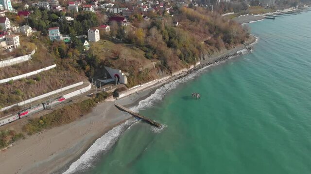 Bird's-eye view of the city in the mountains. The train enters a tunnel next to the sea.