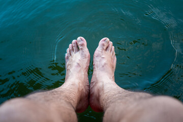 Close-up at human bare foot which is soaking in clearly turquoise water for relaxing. Travel and holiday vacation abstract photo concept.