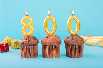 800 Number gold candle on a cupcake against a pastel blue background eight hundred year celebration - obrazy, fototapety, plakaty