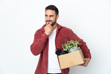 Young caucasian man making a move while picking up a box full of things isolated on white background looking to the side and smiling