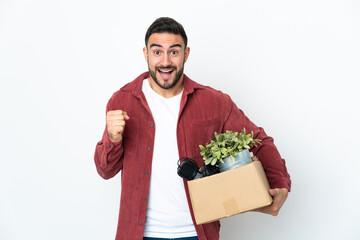 Young caucasian man making a move while picking up a box full of things isolated on white...