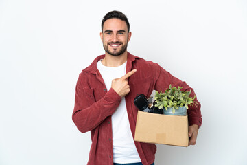 Young caucasian man making a move while picking up a box full of things isolated on white...