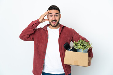 Young caucasian man making a move while picking up a box full of things isolated on white...