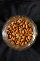 Migdały w dużym szklanym słoju na ciemnym tle