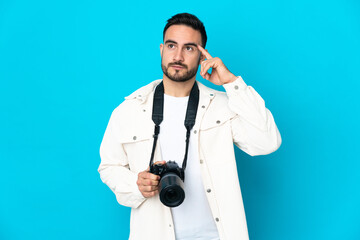 Young photographer man isolated on blue background having doubts and thinking