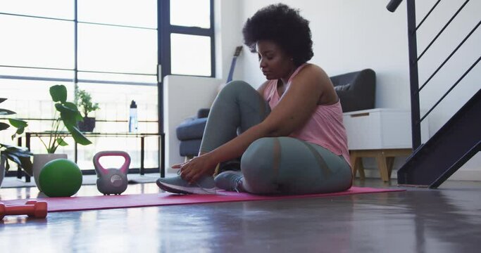 African american female vlogger lying on exercise mat working out