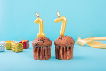 17 Number gold candle on a cupcake against a pastel blue background seventeen year celebration