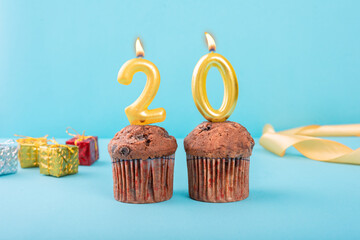 20 Number gold candle on a cupcake against a pastel blue background twenty year celebration