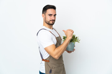 Gardener man holding a plant isolated on white background proud and self-satisfied