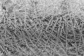 Glass covered with patterns and crystals of frost in winter