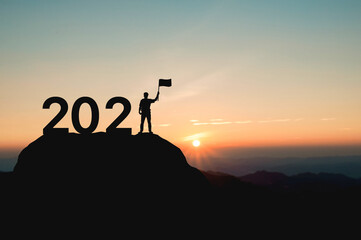 2021 New year Success concept. silhouette of a man holding the winner flag with 2021 on the mountain.