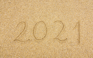 2021 handwritten on beach sand, new year and holiday concept