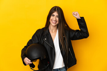 Young caucasian woman holding a motorcycle helmet isolated on yellow background doing strong gesture