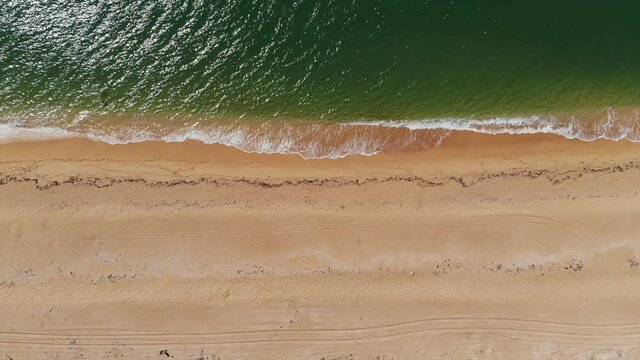Aerial top view of ocean blue waves crashing on the beach. Sea waves and beautiful sandy beach aerial view shot from a drone.