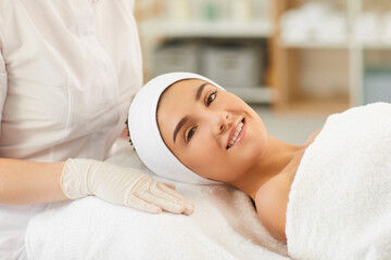 Obraz na płótnie Canvas Smiling young woman looking at camera after procedure of facial massage