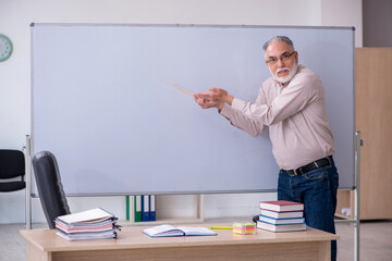 Old male teacher sitting in the classroom