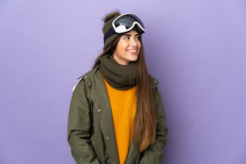 Skier caucasian girl with snowboarding glasses isolated on purple background thinking an idea while looking up