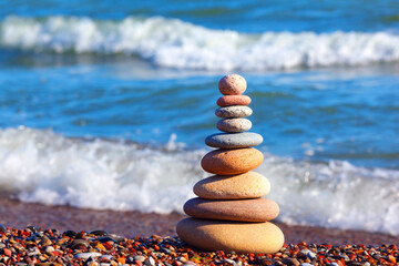 Pyramid of colored pebbles on a background of the summer sea. Concept of harmony, balance and...