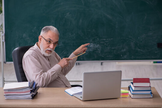 Old male teacher sitting in the classroom