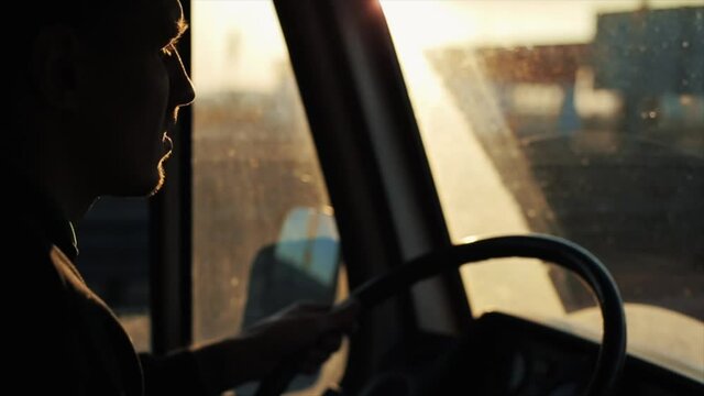 A young man is driving down a busy highway in his van and staring intently at the road. Side view from inside the cab